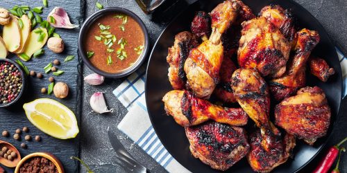 Spicy Grilled Caribbean Jerk Chicken drumsticks and thighs on a black platter on a wooden table